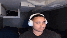 a man wearing headphones and a mustache is sitting in a chair in a dark room .