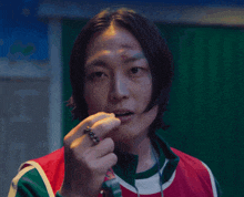 a man with a ring in his mouth is wearing a red green and white jacket