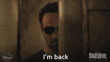 a man wearing sunglasses says i 'm back behind a wall