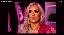 a woman with blonde hair is wearing a pink shirt and a necklace .