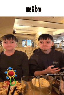 two boys are sitting at a table with a baby rattle in front of them and a caption that says me & bro