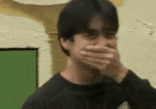 a man is covering his mouth with his hands while laughing .