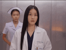 a nurse stands behind a female doctor with a name tag that says ' a '