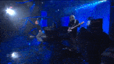 a group of people are playing instruments on a stage in front of a blue background .