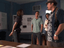 a man in a hawaiian shirt stands in a room with other people