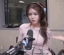 a woman wearing headphones is sitting in front of a microphone in a room .