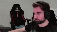 a man with a beard wearing headphones is sitting in front of a computer .