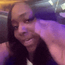 a woman with long black hair is sitting in a chair with purple lights behind her .
