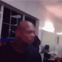 a bald man is standing in a dark room