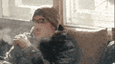a man is sitting on a couch smoking a cigarette .