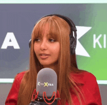 a woman wearing headphones stands in front of a kiss extra logo