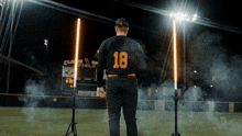a baseball player with the number 18 on his jersey stands on the field