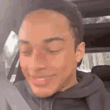 a young man is sitting in the back seat of a car smiling .