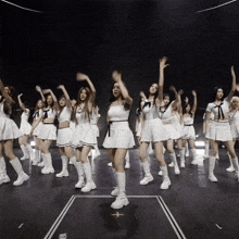 a group of women in white dresses and boots are dancing on a dark stage