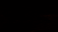 a blurred image of a person holding a gun in a dark room with a red light behind them