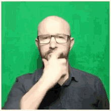 a man with glasses and a beard is making a gesture with his hand .