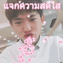 a young man is blowing pink flowers into the air .