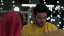 a man in a yellow jacket looks down at something