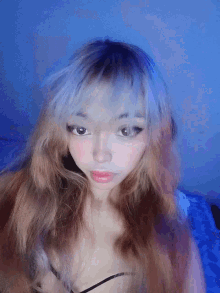 a girl with long blonde hair and blue eyes is wearing a black bra and looking at the camera .
