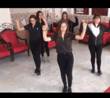 a group of girls are dancing together in a room with red chairs