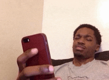 a man is sitting on a couch looking at a cell phone .