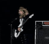 a woman singing into a microphone while playing a white guitar