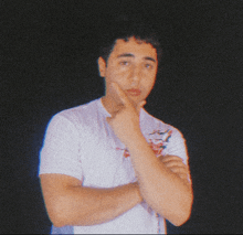 a man in a white shirt has his hand on his chin and looks at the camera