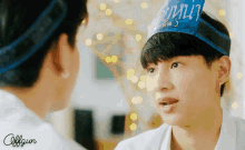 a boy wearing a birthday hat looks at another boy wearing a birthday hat