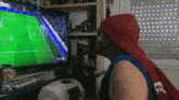 a man is watching a soccer game on a television with a bag of pronazo chips on the desk