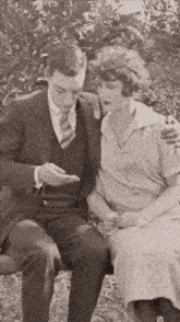 a black and white photo of a man and woman sitting on a bench