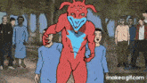 a group of people are standing around a red monster with a blue face and horns