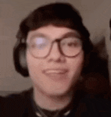 a close up of a man wearing glasses and headphones smiling .