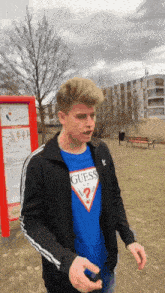 a young man wearing a blue guess t-shirt