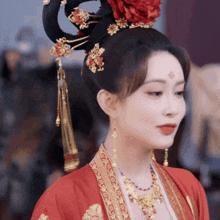 a woman with a red flower in her hair is wearing a red dress