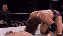 a wrestler in purple shorts is kneeling on the floor