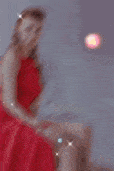 a woman in a red dress sits on a chair in front of a mirror