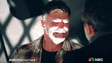 a man in a plaid shirt is talking to another man with nbc destination x written on the bottom of the screen