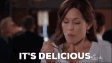 a woman is eating food with a fork and spoon and the words `` it 's delicious '' are written above her .