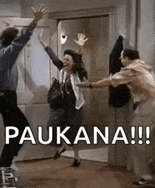a man and a woman are jumping in the air in a room with their arms in the air .