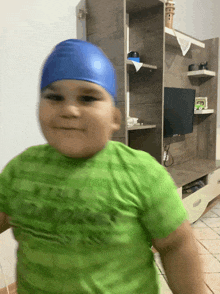 a boy wearing a blue swim cap and a green shirt