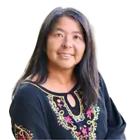 a woman wearing a black shirt with a floral embroidered neckline smiles for the camera