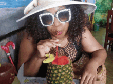 a woman wearing sunglasses is drinking from a pineapple