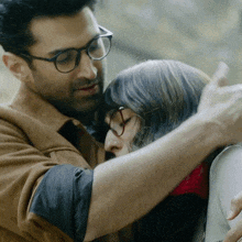 a man wearing glasses is hugging a woman who is wearing glasses