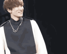a young man wearing a black and white sweater and a chain necklace
