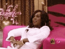 a woman is sitting on a pink couch in a room .