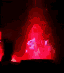a blurred image of a person standing in front of a red fire