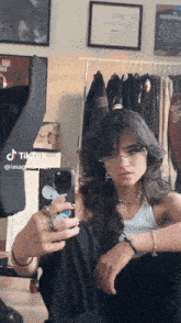 a girl is taking a selfie in front of a mirror while wearing glasses and a necklace .