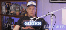 a man is sitting in front of a microphone with the words gross dark web written on the screen behind him .
