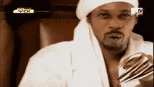 a man wearing a white robe and a white head scarf is sitting in front of a tv screen that says monster yo
