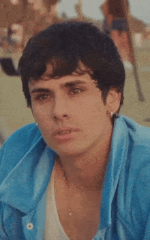 a young man wearing a blue shirt and a white tank top